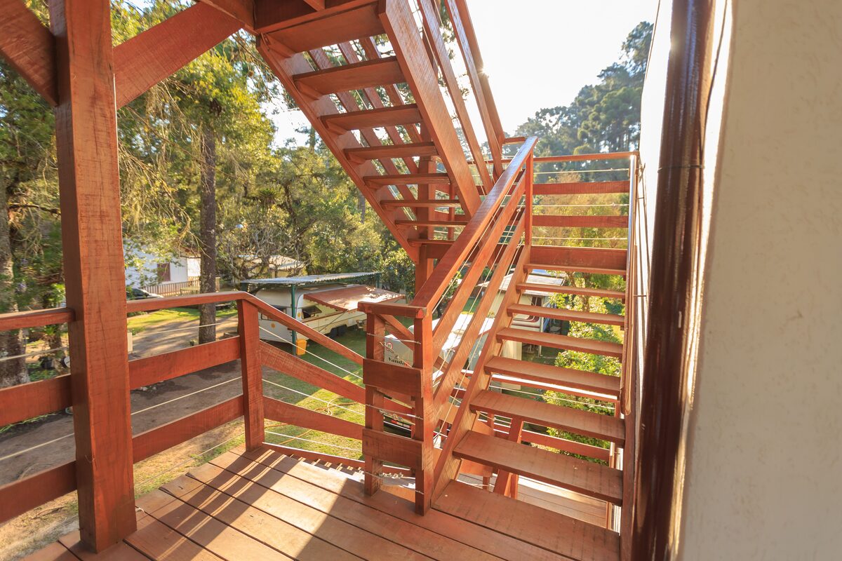Multi-level wooden deck and staircase structure in sunlight among trees
